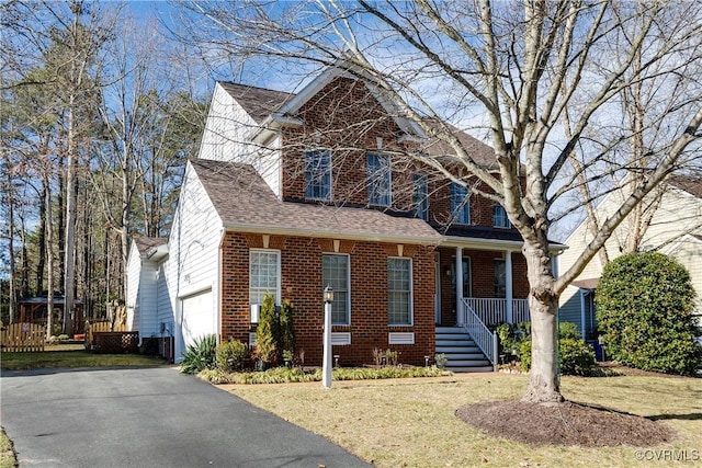 view of front of property featuring a garage, brick siding, a front lawn, and aphalt driveway