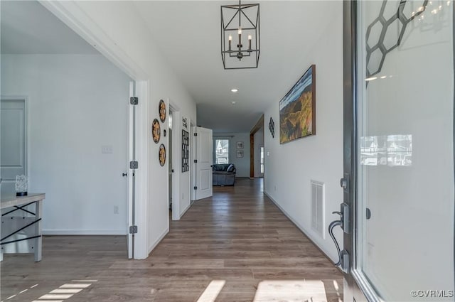 hallway with a chandelier and light hardwood / wood-style floors