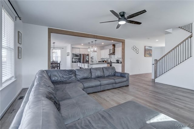 living room featuring ceiling fan with notable chandelier and light hardwood / wood-style floors