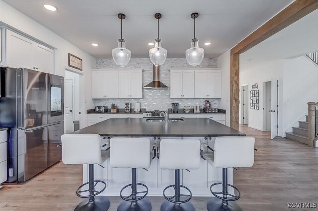 kitchen with stainless steel fridge, sink, a center island with sink, and white cabinets