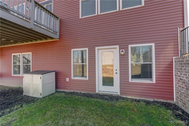 entrance to property featuring a lawn and a balcony