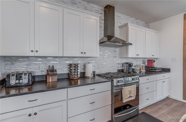 kitchen with white cabinetry, gas stove, backsplash, and wall chimney exhaust hood