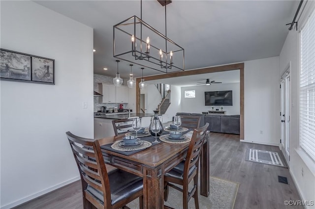 dining space featuring dark hardwood / wood-style floors and ceiling fan with notable chandelier