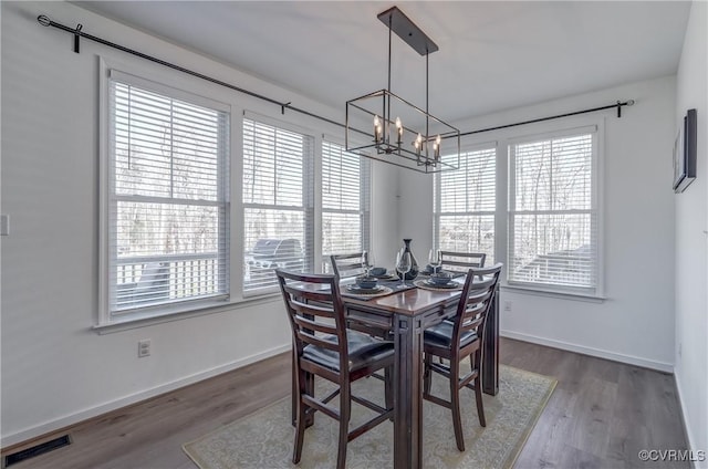 dining area with a notable chandelier, wood-type flooring, and a healthy amount of sunlight