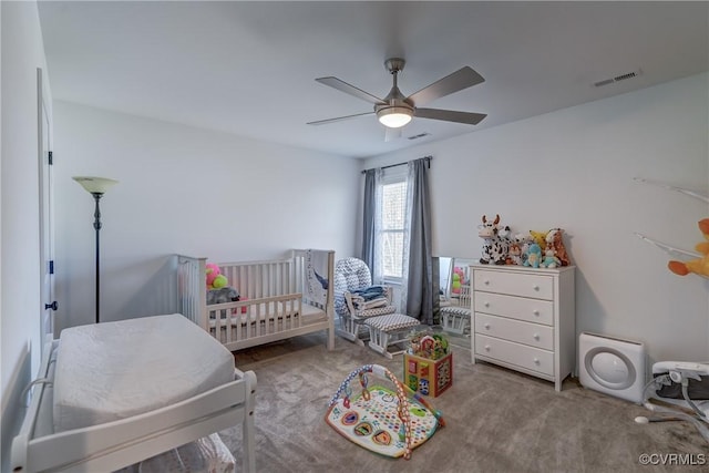 bedroom with light carpet, a nursery area, and ceiling fan