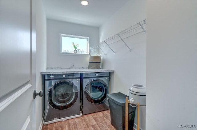 laundry area with washer and clothes dryer and light hardwood / wood-style flooring