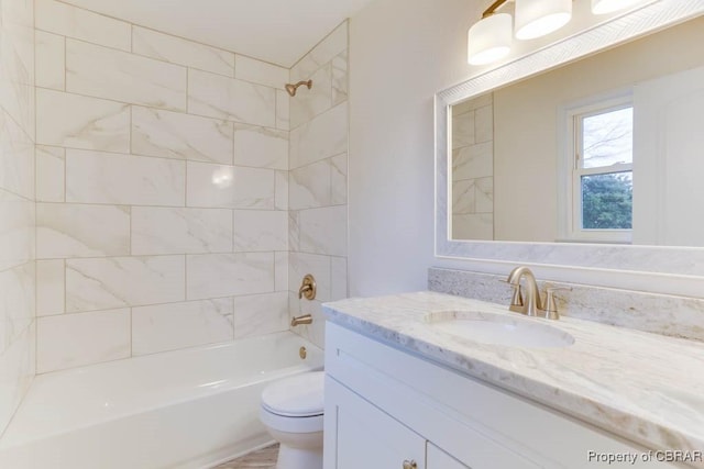 full bathroom featuring tiled shower / bath, vanity, and toilet