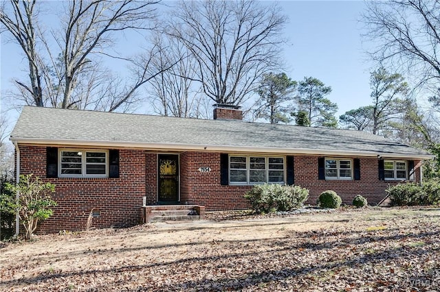 ranch-style house featuring crawl space, a shingled roof, a chimney, and brick siding