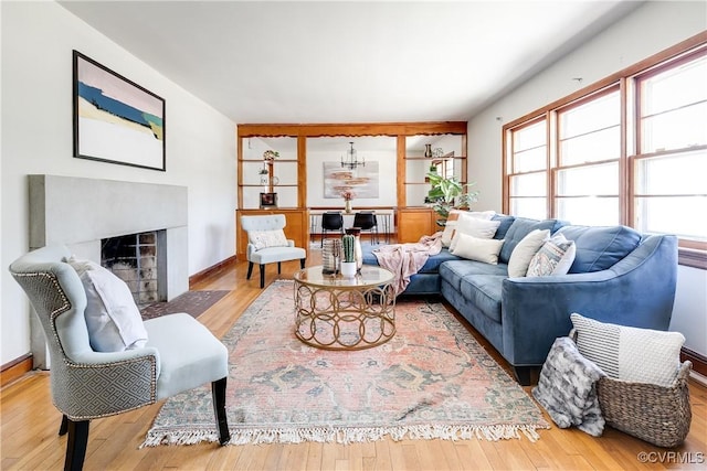 living area featuring wood finished floors, a fireplace with flush hearth, and baseboards