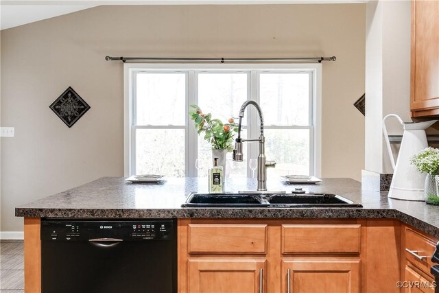 kitchen featuring plenty of natural light, dark countertops, dishwasher, and a sink