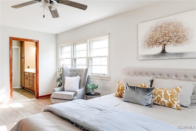 bedroom featuring baseboards, ensuite bath, a ceiling fan, and light wood-style floors