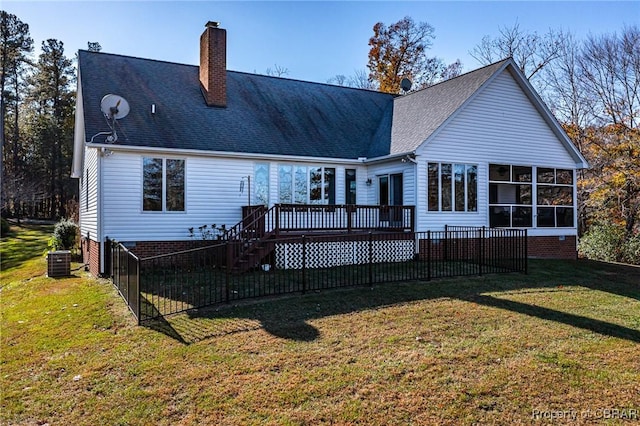 back of house featuring central AC, a sunroom, a deck, and a lawn