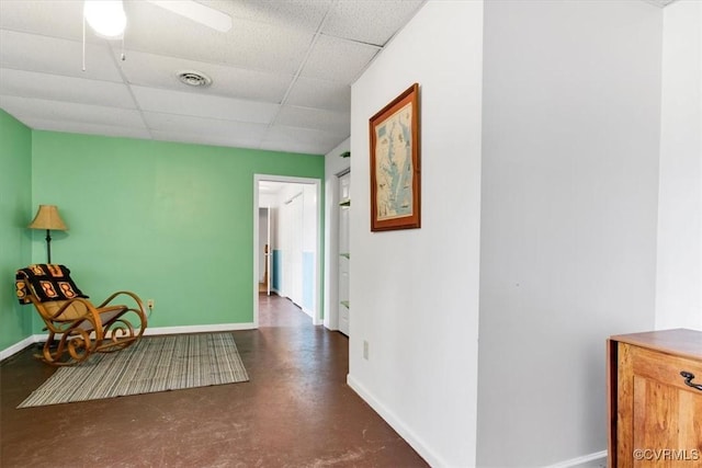 sitting room featuring ceiling fan and a drop ceiling