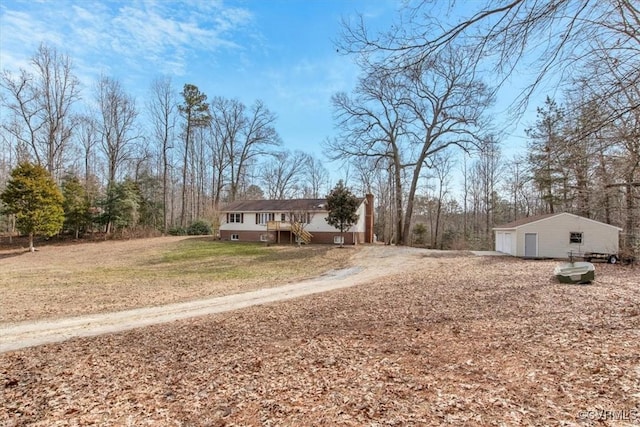 view of front of home with a garage, an outdoor structure, and a front lawn