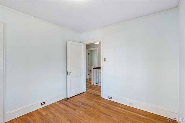 empty room with baseboards, light wood-style floors, and crown molding