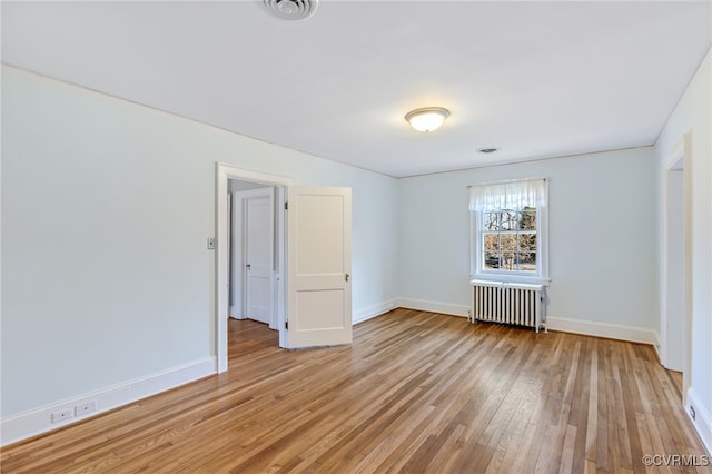 unfurnished room featuring light wood finished floors, radiator heating unit, visible vents, and baseboards