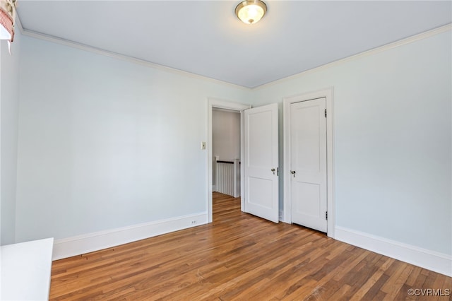 unfurnished bedroom featuring crown molding, baseboards, and wood finished floors