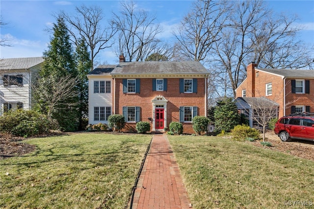 view of front of home featuring brick siding, a chimney, and a front yard