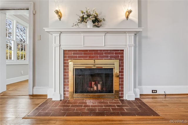 room details with baseboards, a tiled fireplace, and wood finished floors