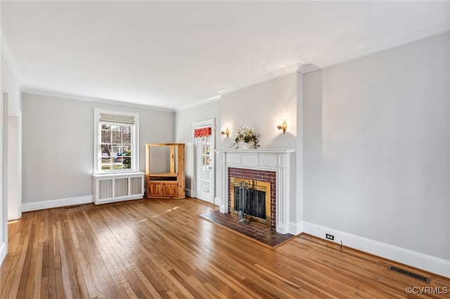 unfurnished living room with crown molding, a fireplace, visible vents, baseboards, and hardwood / wood-style flooring