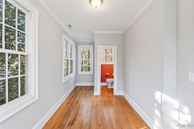 unfurnished bedroom featuring crown molding, visible vents, ensuite bathroom, light wood-style floors, and baseboards