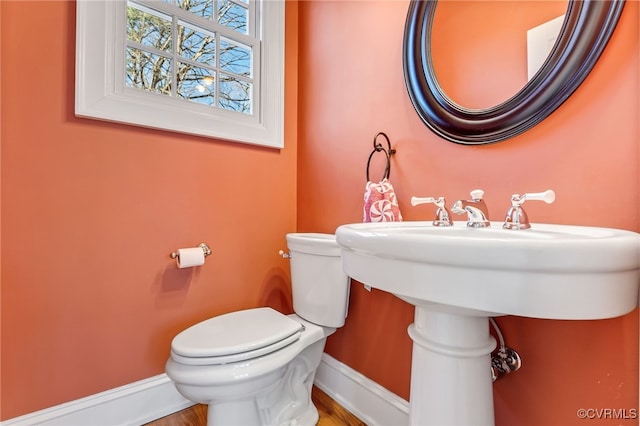 half bathroom with toilet and baseboards