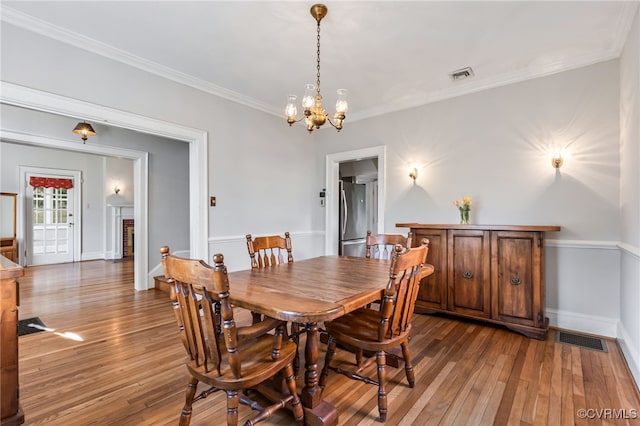 dining space featuring crown molding, visible vents, a fireplace, and hardwood / wood-style floors