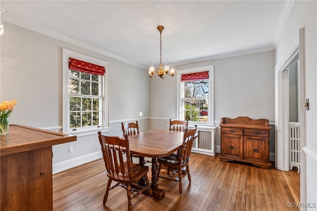 dining space with baseboards, a notable chandelier, ornamental molding, and hardwood / wood-style floors