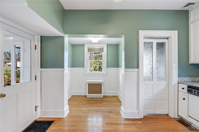 interior space featuring light wood-style flooring, visible vents, white cabinetry, and dishwasher