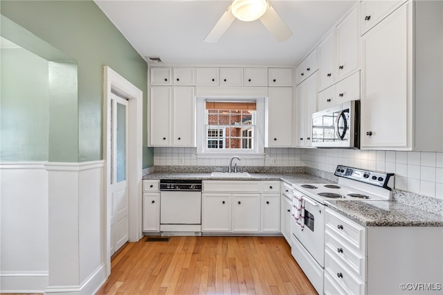 kitchen featuring white appliances, white cabinetry, visible vents, and a sink