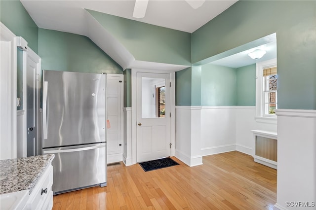 kitchen featuring light wood-style floors, freestanding refrigerator, white cabinets, and light stone counters