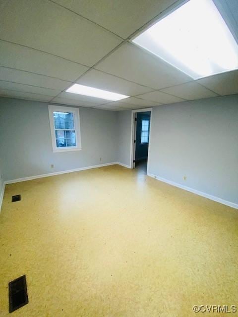 basement featuring a paneled ceiling and a healthy amount of sunlight