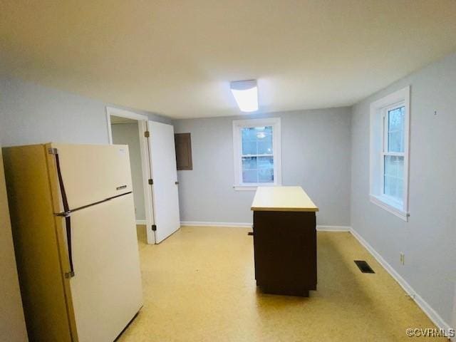 kitchen with dark brown cabinetry and white fridge