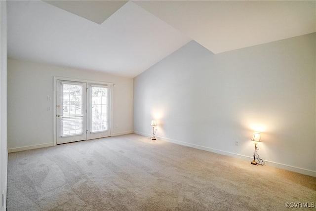 carpeted empty room featuring baseboards and vaulted ceiling