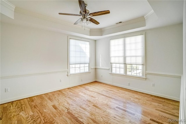 spare room featuring plenty of natural light, crown molding, a tray ceiling, and wood finished floors