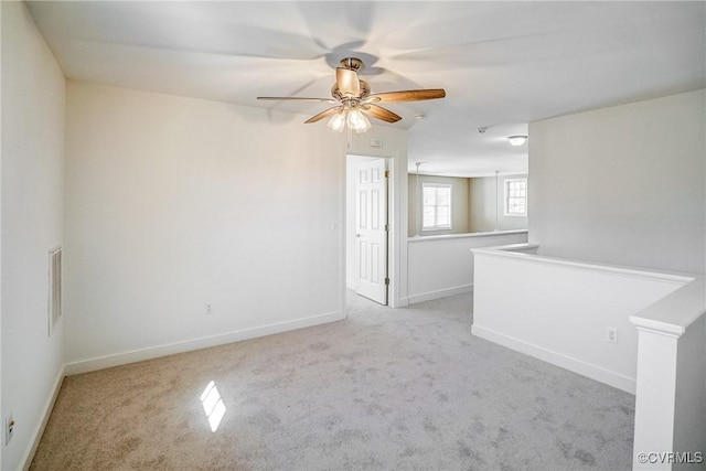 carpeted spare room with ceiling fan, visible vents, and baseboards