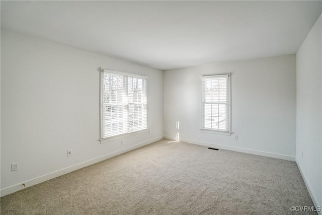 unfurnished room with plenty of natural light, carpet flooring, visible vents, and baseboards