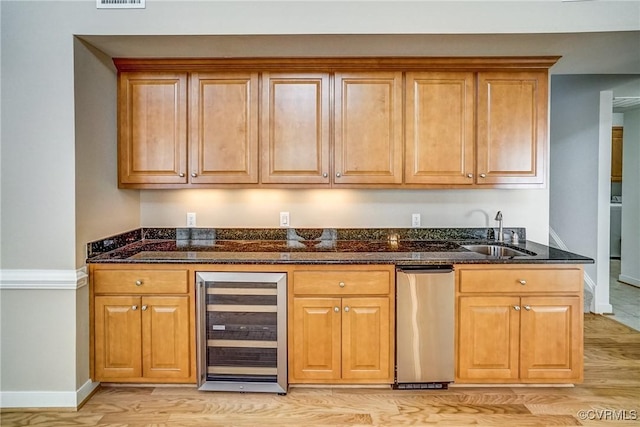 kitchen with dark stone counters, wine cooler, a sink, and brown cabinets