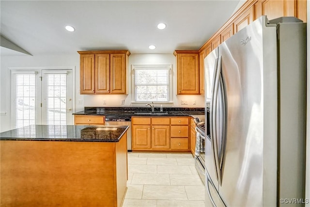 kitchen with stainless steel appliances, recessed lighting, a sink, and dark stone countertops