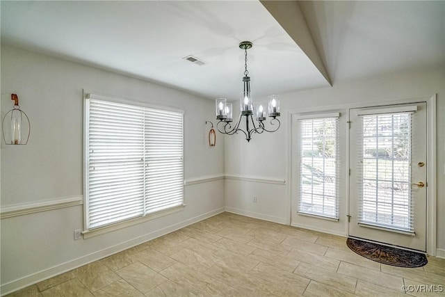 unfurnished dining area with baseboards, visible vents, and a notable chandelier