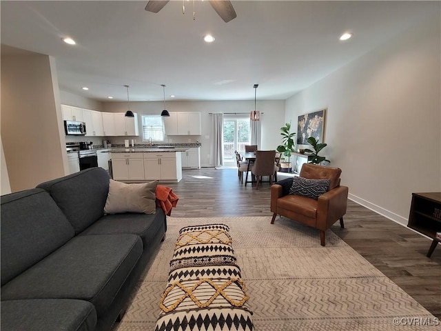 living room featuring ceiling fan, wood-type flooring, and sink