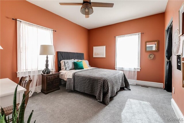 carpeted bedroom featuring multiple windows and ceiling fan