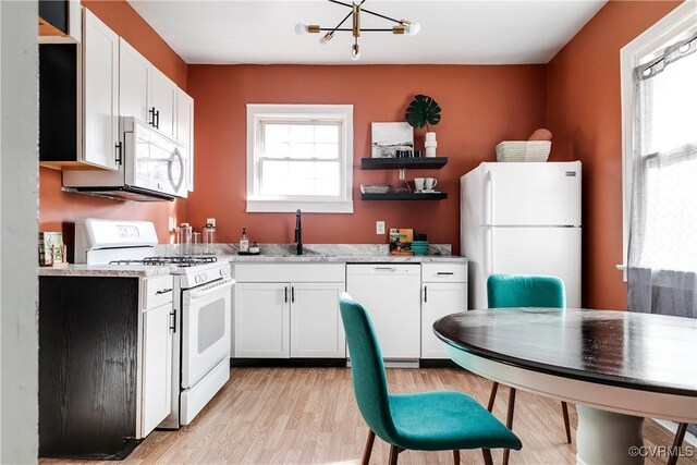 kitchen featuring an inviting chandelier, white cabinets, white appliances, light stone countertops, and light wood-type flooring