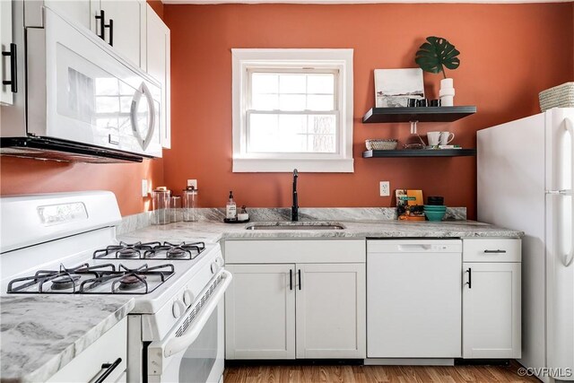 kitchen with white cabinetry, white appliances, sink, and light wood-type flooring