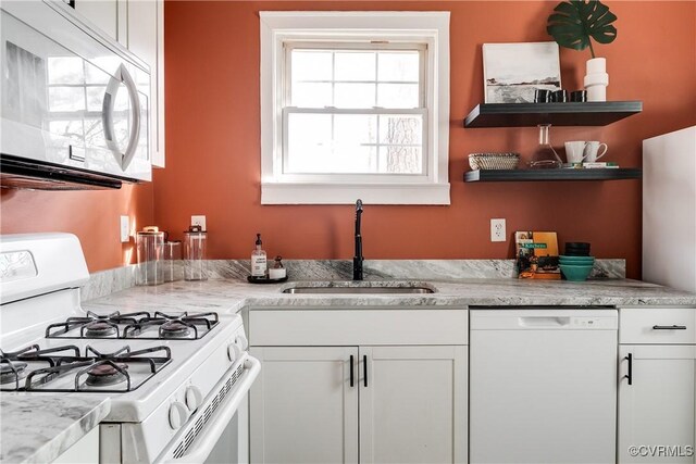 kitchen featuring white cabinetry, sink, light stone counters, and white appliances