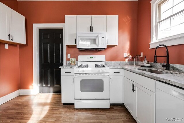 kitchen with white cabinetry, sink, white appliances, and light hardwood / wood-style flooring