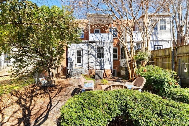 back of house featuring fence and brick siding