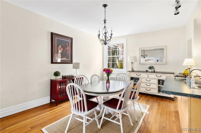 dining space with a chandelier, light wood-style flooring, and baseboards