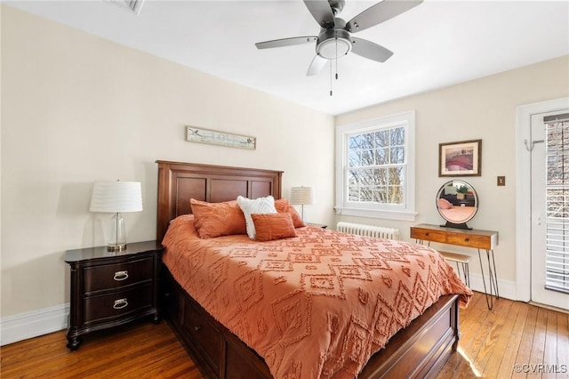 bedroom featuring a ceiling fan, radiator heating unit, baseboards, and hardwood / wood-style floors