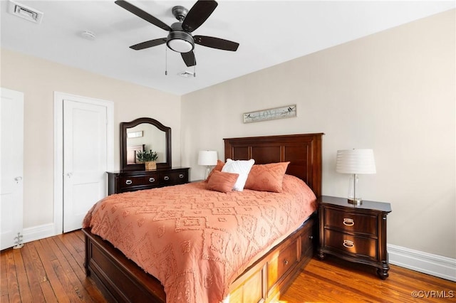 bedroom with a ceiling fan, wood-type flooring, visible vents, and baseboards